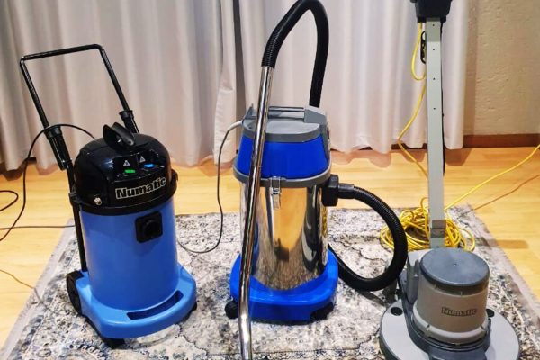 Professional carpet and floor cleaning equipment by Clean Route Services, featuring Numatic vacuum cleaners and floor scrubber on patterned rug